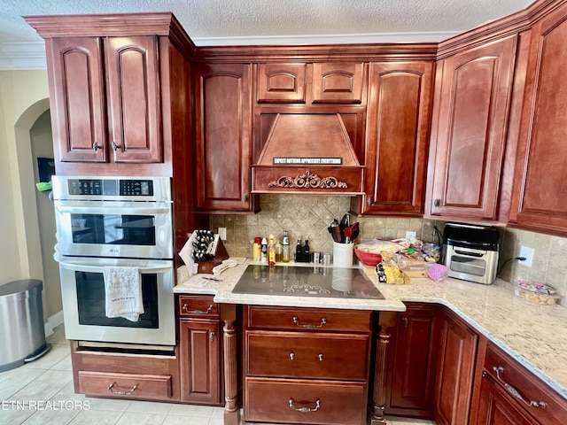 kitchen featuring double oven, black electric cooktop, decorative backsplash, light tile patterned flooring, and custom exhaust hood