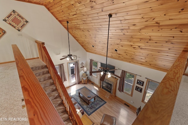 unfurnished living room with ceiling fan, high vaulted ceiling, wooden ceiling, and light colored carpet