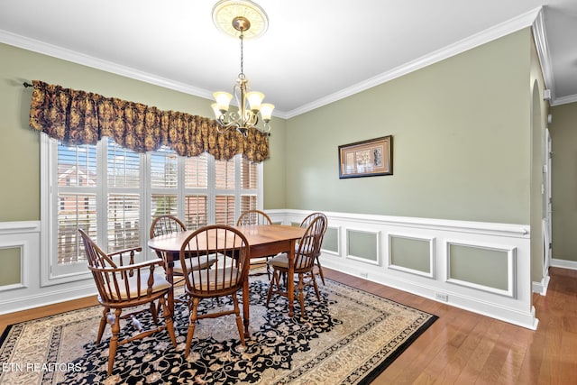 dining room featuring wood-type flooring, crown molding, and a notable chandelier