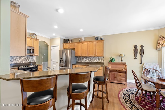 kitchen featuring appliances with stainless steel finishes, a kitchen breakfast bar, backsplash, kitchen peninsula, and light hardwood / wood-style flooring