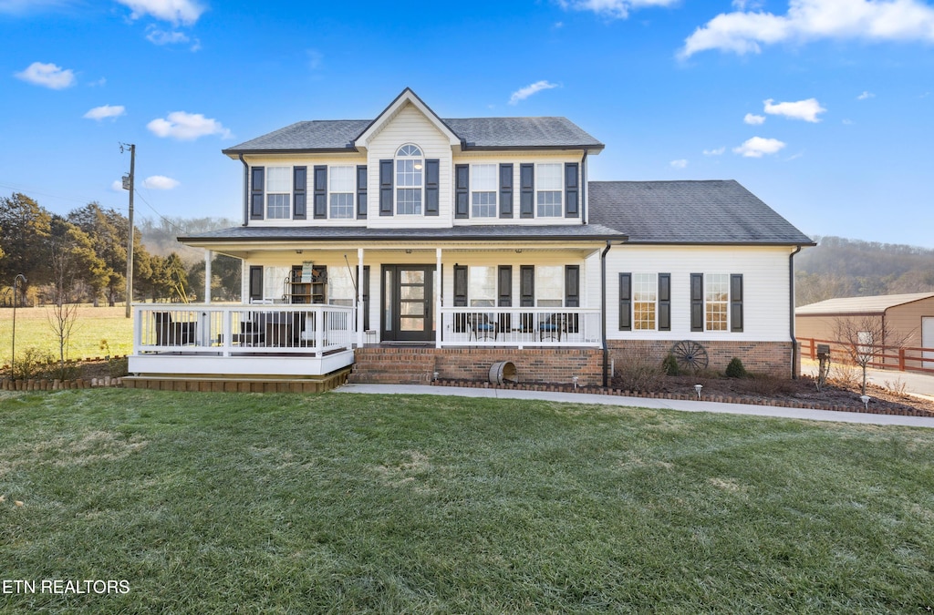 colonial-style house featuring a porch and a front lawn