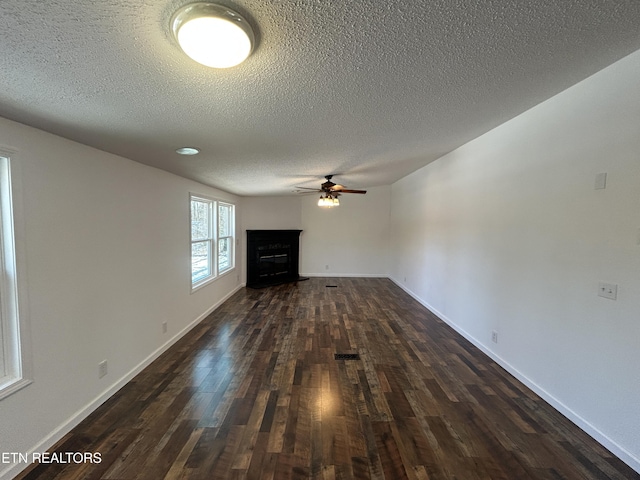 unfurnished living room featuring a textured ceiling, dark wood-type flooring, and ceiling fan