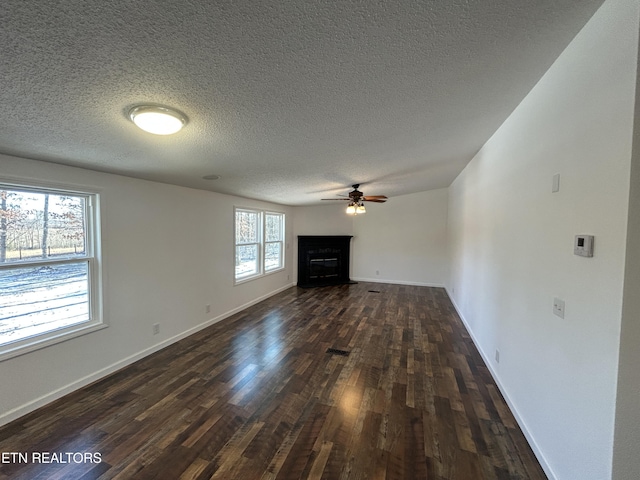 unfurnished living room with a textured ceiling, dark wood-type flooring, and ceiling fan