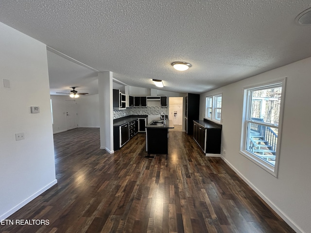 kitchen with a kitchen island, tasteful backsplash, sink, ceiling fan, and dark wood-type flooring