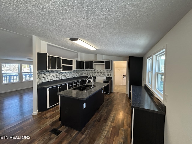 kitchen with an island with sink, lofted ceiling, sink, and backsplash