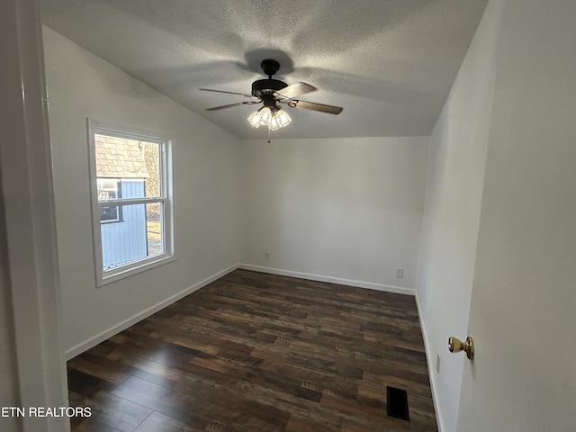 spare room featuring ceiling fan, vaulted ceiling, dark wood-type flooring, and a textured ceiling