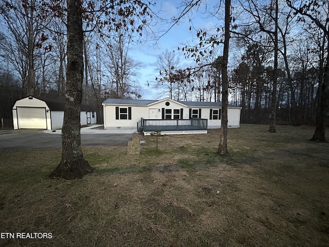 manufactured / mobile home featuring a garage, a wooden deck, an outbuilding, and a front yard