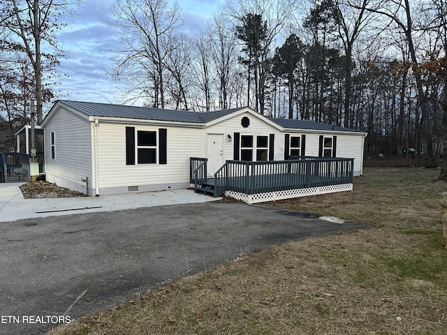 manufactured / mobile home with a wooden deck and a front lawn