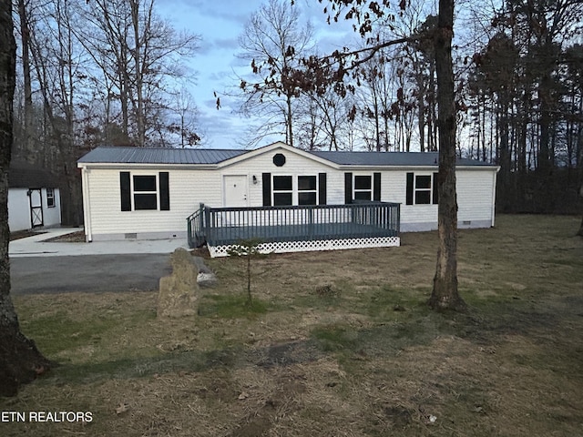 manufactured / mobile home featuring a wooden deck, a front lawn, and a shed