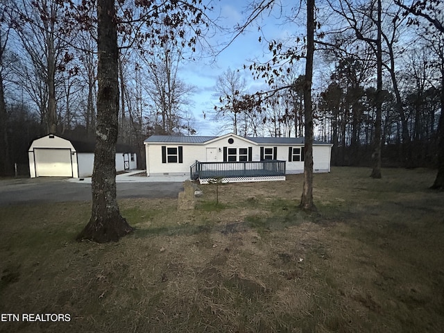 manufactured / mobile home featuring a garage, a wooden deck, an outdoor structure, and a front lawn