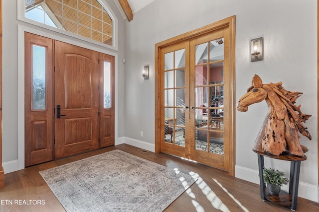 foyer with wood-type flooring, french doors, and vaulted ceiling with beams