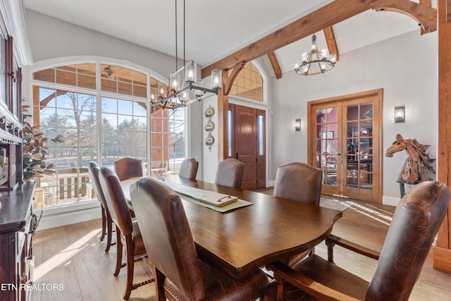 dining room with an inviting chandelier, light hardwood / wood-style floors, french doors, and lofted ceiling with beams