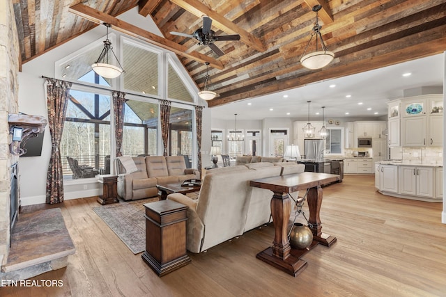 living room featuring beamed ceiling, light hardwood / wood-style floors, ceiling fan with notable chandelier, and high vaulted ceiling