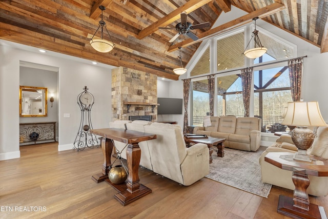 living room with beam ceiling, a fireplace, light hardwood / wood-style floors, and high vaulted ceiling