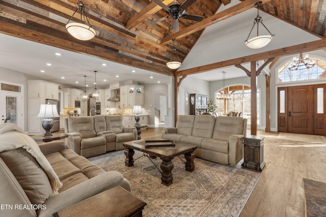 living room featuring beamed ceiling, ceiling fan with notable chandelier, light hardwood / wood-style flooring, and high vaulted ceiling