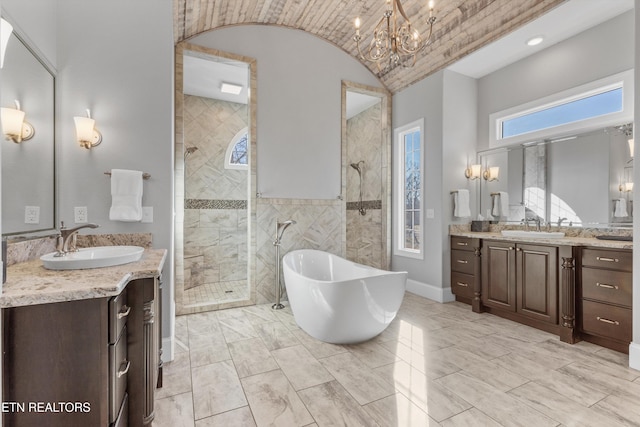 bathroom with shower with separate bathtub, vanity, and a notable chandelier