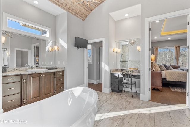 bathroom featuring a bath, brick ceiling, a chandelier, and vanity