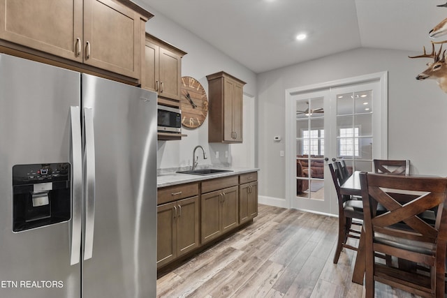 kitchen featuring light hardwood / wood-style floors, appliances with stainless steel finishes, french doors, light stone counters, and sink