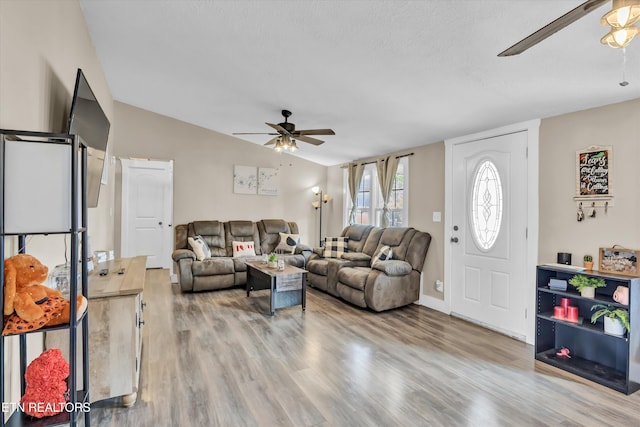 living room featuring light hardwood / wood-style flooring, a textured ceiling, vaulted ceiling, and ceiling fan