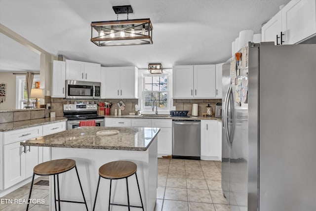 kitchen featuring white cabinetry, stainless steel appliances, decorative light fixtures, and sink