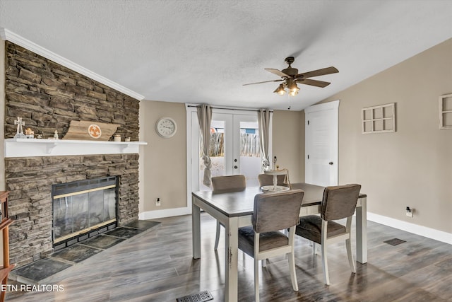 dining space featuring a fireplace, dark hardwood / wood-style flooring, ceiling fan, a textured ceiling, and french doors