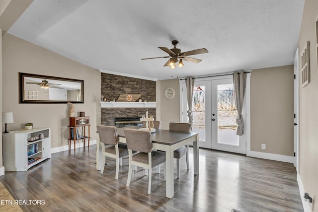 dining area featuring french doors, a fireplace, a textured ceiling, and hardwood / wood-style flooring