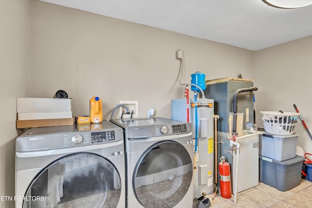 washroom with light tile patterned flooring, washer and clothes dryer, and water heater