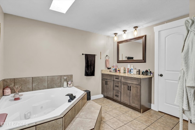 bathroom featuring tile patterned floors, a skylight, a textured ceiling, vanity, and a relaxing tiled tub