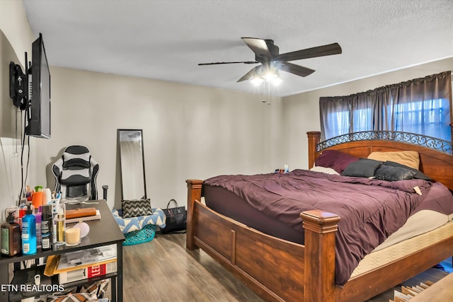 bedroom featuring ceiling fan, hardwood / wood-style flooring, and a textured ceiling