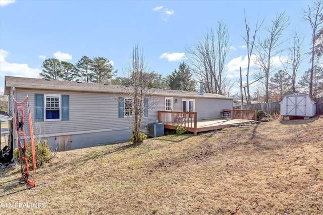 back of house with a wooden deck, a yard, central AC, and a storage shed