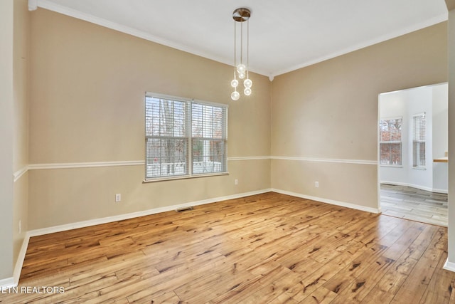 spare room featuring a chandelier, light wood-type flooring, and crown molding