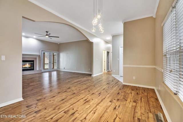 unfurnished living room featuring a healthy amount of sunlight, light hardwood / wood-style floors, ceiling fan, and crown molding