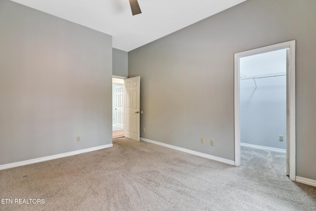 unfurnished bedroom with a closet, a spacious closet, ceiling fan, and light colored carpet