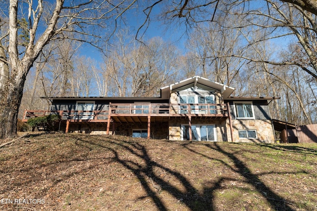 rear view of property with a wooden deck and a lawn