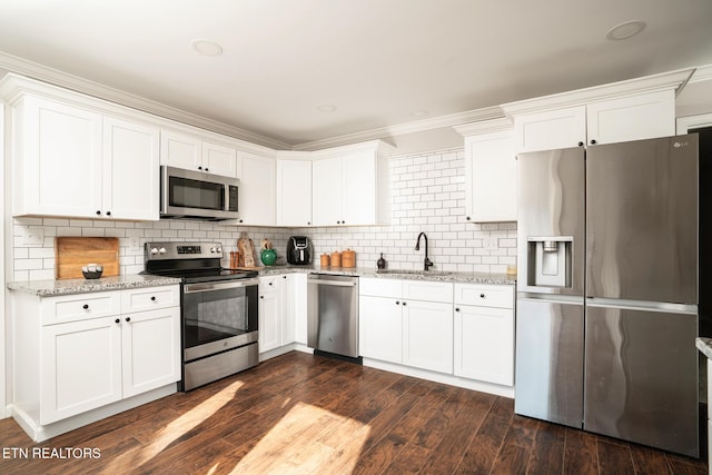 kitchen featuring appliances with stainless steel finishes, decorative backsplash, white cabinets, and sink