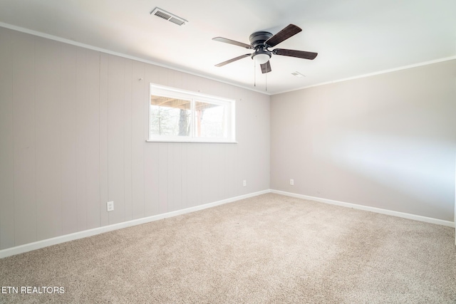 carpeted spare room with ceiling fan and ornamental molding