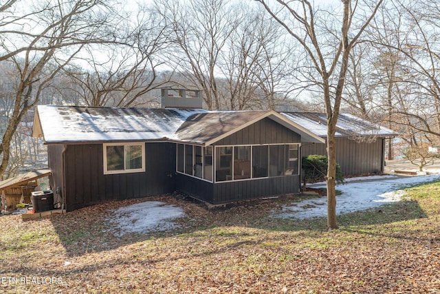 back of property with central AC and a sunroom