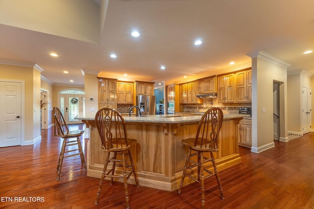 kitchen with a breakfast bar area, dark wood finished floors, stainless steel fridge with ice dispenser, and light stone countertops