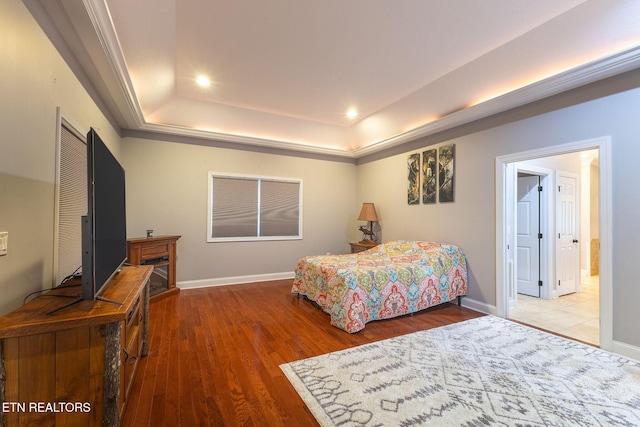 bedroom featuring a raised ceiling, recessed lighting, wood finished floors, and baseboards