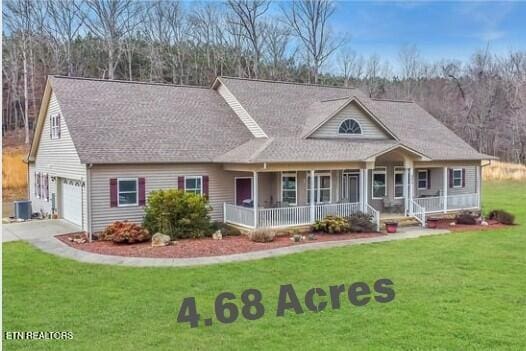 view of front of home featuring covered porch, cooling unit, a front lawn, and a garage