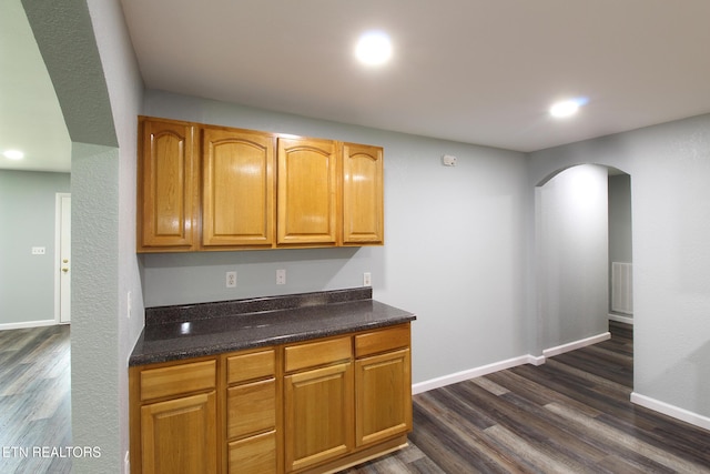 228 Pedigo Rd, Madisonville, TN 37354 - kitchen with arched walkways, dark wood-type flooring, recessed lighting, brown cabinets, and dark stone countertops
