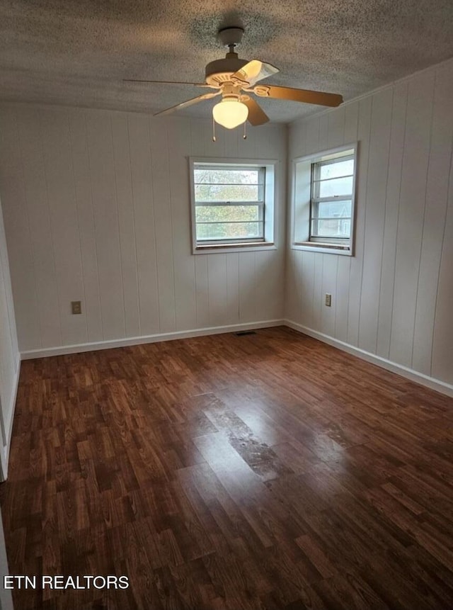 empty room with a textured ceiling, dark hardwood / wood-style flooring, and ceiling fan