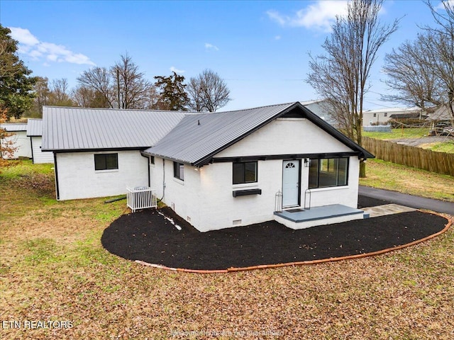 rear view of property featuring central AC unit and a lawn