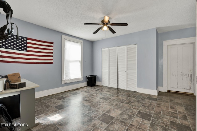 unfurnished bedroom featuring ceiling fan, a textured ceiling, and a closet