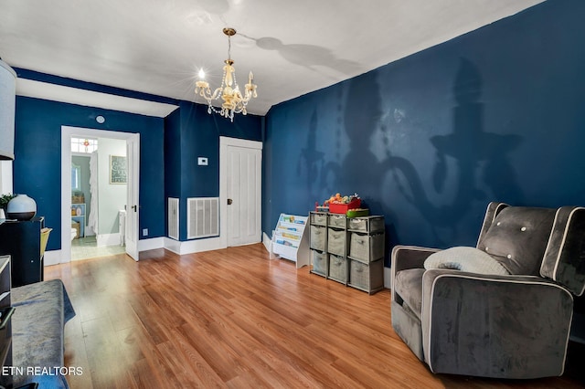 sitting room with hardwood / wood-style flooring and an inviting chandelier