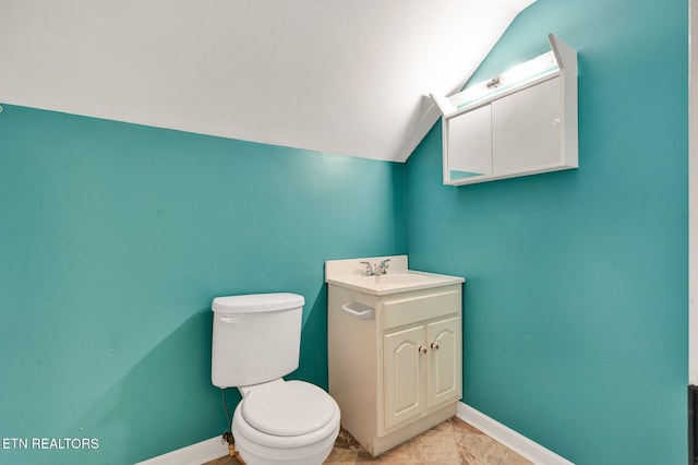 bathroom with vaulted ceiling, toilet, tile patterned floors, and vanity