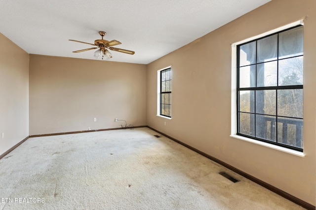 carpeted empty room featuring ceiling fan and plenty of natural light