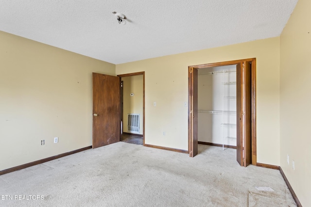 unfurnished bedroom featuring a textured ceiling, a closet, and light colored carpet