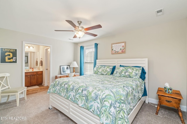 bedroom featuring ceiling fan, light colored carpet, and connected bathroom