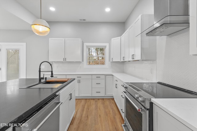 kitchen with white cabinetry, appliances with stainless steel finishes, wall chimney exhaust hood, and sink